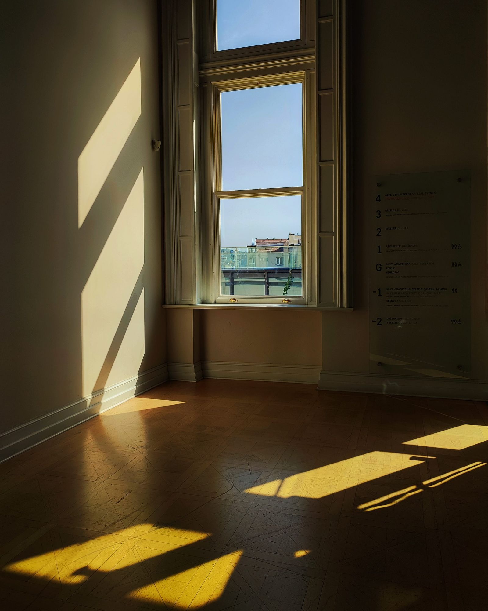 Late afternoon light falling through a tall window into a quiet, empty room